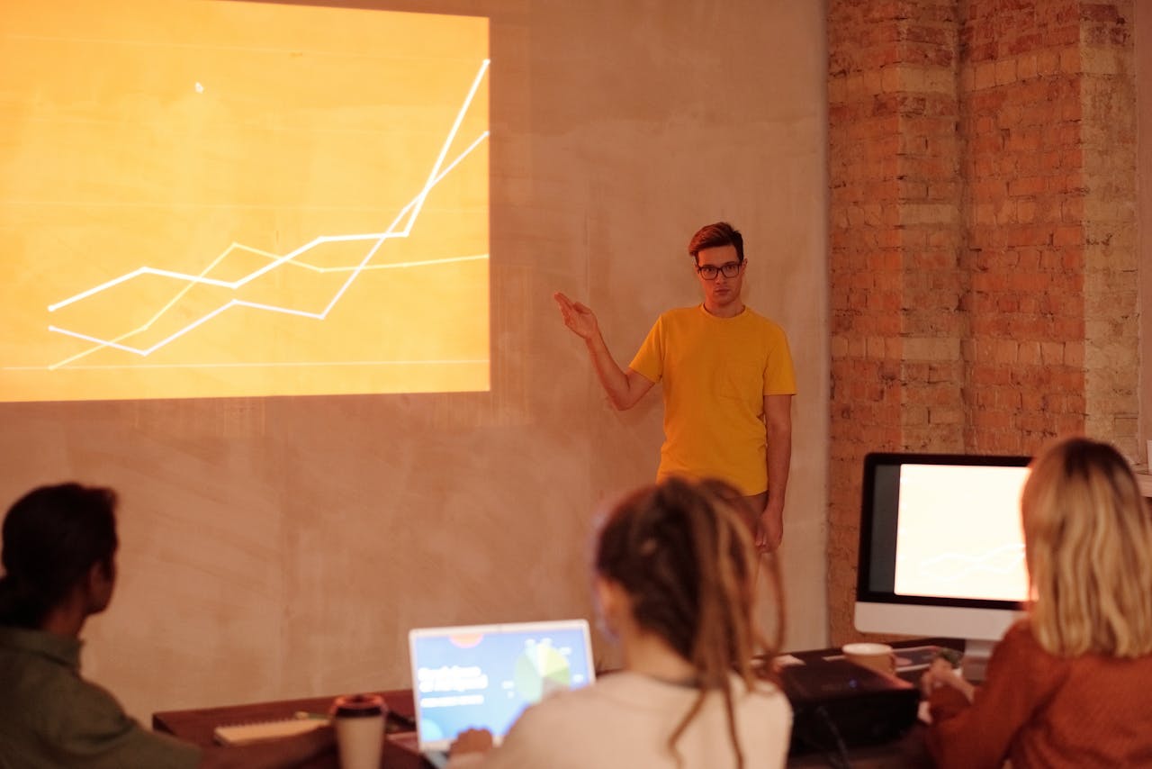 A young man gives a presentation on data analysis in a modern office setting.